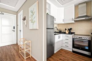 迪拜Luxury apartment at Discovery的厨房配有白色橱柜和不锈钢冰箱