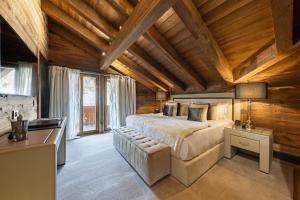 格施塔德Ultima Gstaad Residences的一间带一张大床的卧室,位于一个拥有木制天花板的房间