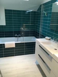 拉波勒Chez Lilette的浴室铺有绿色瓷砖,配有浴缸和水槽。