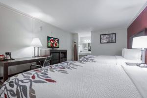 福雷斯特城Red Roof Inn Forrest City的酒店客房设有一张大床和一张书桌。