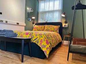 克劳奇河畔伯纳姆The Boot Room Ground Floor Studio Apartment的一间卧室配有一张带彩色床罩和桌子的床。