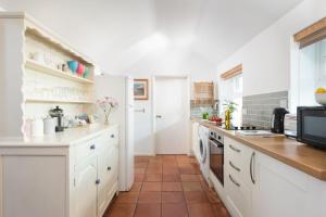 卡比斯贝Laity Vean Hideaway的厨房配有白色橱柜和瓷砖地板。