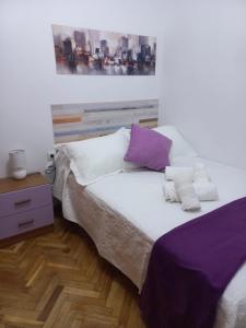 阿维拉CASA ESQUILAS的一间卧室配有一张带紫色和白色枕头的床