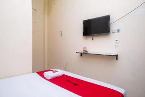 SeturanRedDoorz near Plaza Ambarrukmo Yogyakarta的客房设有一张床和一台平面电视。