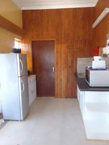 PrieskaHolope Self-Catering Accomm的厨房配有白色冰箱和木墙