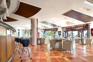 艾阿卡艾美阿尔阿卡海滩度假酒店的餐厅设有酒吧,配有桌椅