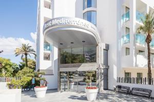 萨洛贝斯特梅迪特拉内奥 酒店的一座白色的大建筑,前面有棕榈树