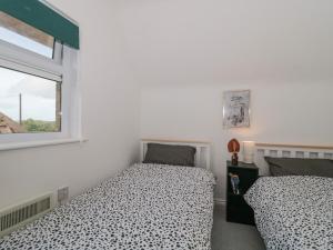 史云顿38 Clyffe Pypard的一间卧室设有两张床和窗户。