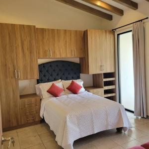 帕茨库卡罗Casita En Patzcuaro的一间卧室配有一张带木制橱柜和红色枕头的床。