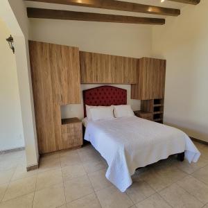 帕茨库卡罗Casita En Patzcuaro的一间卧室配有一张大床和红色床头板