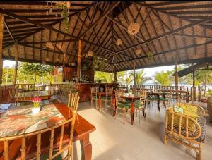 La Tranquilidad Beach Club的餐厅设有木桌和椅子以及大型天花板。