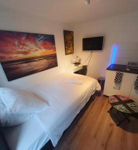 海牙Cozy Garden House kijkduin Beach的卧室配有白色的床和电视。