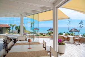 哥斯达雷Villa Escargot Luxury in Costa Rei Beach的一个带桌椅的庭院和大海