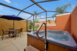 基西米Encantada Resort Vacation Townhomes by IDILIQ的庭院内的热水浴池配有桌子和遮阳伞