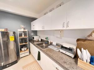 奥隆阿波Charm’s Place的厨房配有白色橱柜和不锈钢冰箱