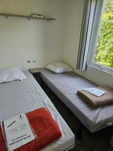 BoofzheimMobil-home climatisé (proximité EUROPA PARC)的两张床位于带窗户的房间内