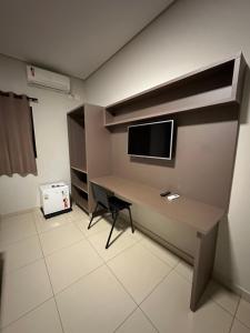 里梅拉Shafira Hotel的客房设有一张桌子,墙上配有电视