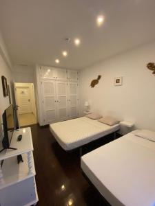 法鲁Blife Sun Hostel的白色的客房配有两张床和电视。