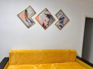 阿拉木图2-х комнатная в центре район ЦУМа的黄色沙发上方的四幅画墙