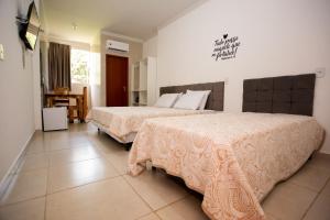 阿拉沙Ribeiro Suit's Hotel的酒店客房设有两张床和一张桌子。
