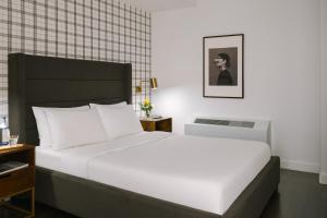 纽约Sonder at One Platt的卧室配有一张白色大床和一张男子肖像