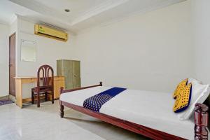 柴瑞海滩SPOT ON 81226 Cherai Rest Home的一间卧室配有一张床、一张桌子和一把椅子