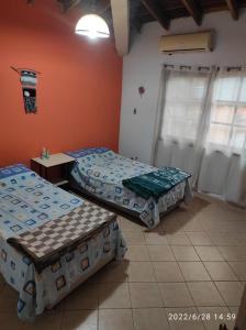 LuqueCasa de 4 habitaciones con piscina en barrio cerrado a 5 minutos del Aeropuerto Internacional的配有橙色墙壁和窗户的客房内的两张床