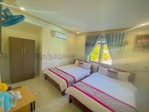 惹岛KHÁCH SẠN HƯNG THỊNH - Lý Sơn的一间卧室设有两张床、一张桌子和一个窗口
