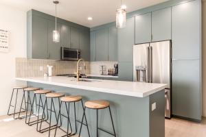 盐湖城BRAND NEW Modern 5 Bd, 3 Story Home in Sugarhouse!的厨房配有灰色橱柜和带凳子的台面