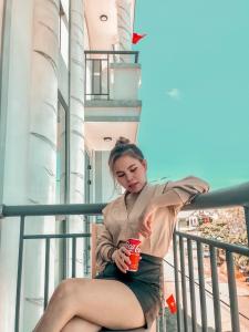 惹岛KHÁCH SẠN HƯNG THỊNH - Lý Sơn的坐在阳台上喝一杯的女人