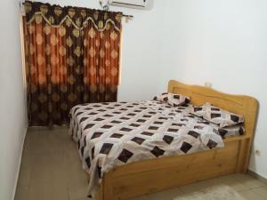 洛美HEBERTOGO TOKOIN CASABLANCA的一间卧室配有一张带窗帘的木床