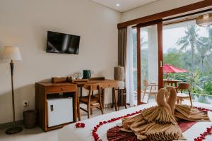乌布Sanubari Ubud的一间卧室配有一张带书桌和电视的床。