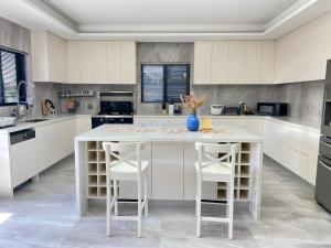 悉尼Penshurst Guest House的白色的厨房配有一张桌子和两张凳子