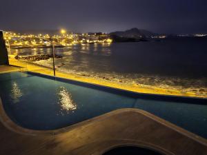 圣巴托洛Departamento de Playa San Bartolo Ocean Reef - SOL, ARENA Y MAR的游泳池,晚上可欣赏到水景