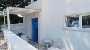 马丁纳弗兰卡Casa Vacanze Villa Greca的白色的房子,设有蓝色的门和桌椅