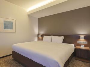鹿儿岛鹿儿岛JR九州酒店的一张大床,位于酒店带两盏灯的房间