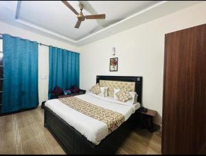 齐拉克普尔Hotel Sunkriti Resort的一间卧室配有一张带蓝色窗帘的大床