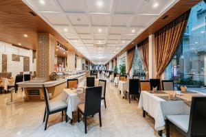 岘港Eden Plaza Da Nang Hotel的餐厅设有桌椅和窗户。