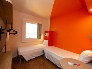 累西腓ibis budget Recife Jaboatão的橙色墙壁的客房内的两张床