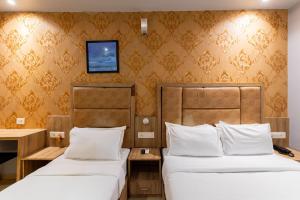 孟买LOTUS GRAND HOTEL MUMBAI的酒店客房设有两张床和一台墙上的电视。