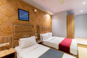 孟买LOTUS GRAND HOTEL MUMBAI的酒店客房设有两张床和一台墙上的电视。