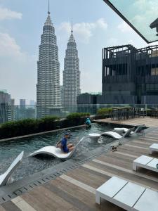吉隆坡KLCC Ritz Residence STAR的坐在有建筑物的游泳池里的船上的女人