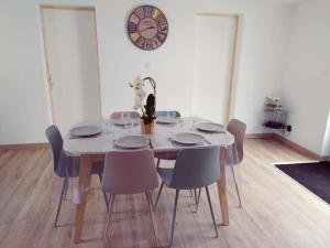 维桑T3 - Appartement jardin Wissant 6 personnes的餐桌、椅子和墙上的时钟