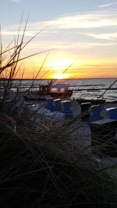岑平Ferienwohnungen Villa Waldblick的海滩上的船只在海洋上日落
