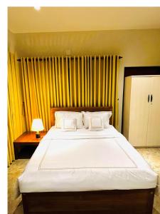 尼甘布Ceylon Kingsmen Garden Hotel - Katunayake的卧室配有一张白色大床和黄色窗帘