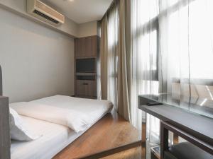 新加坡Amrise Hotel Kitchener, Check In 9PM, Check Out 8AM的一间卧室配有一张床、一张书桌和一个窗户。