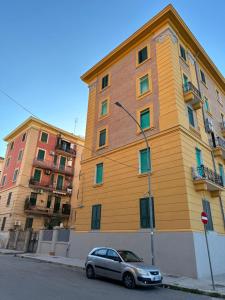福贾Altopiano Rooms的一座黄色的建筑,前面有一辆汽车