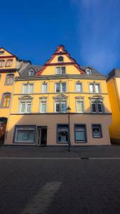 科布伦茨Historisches Haus am Fuße der Festung Ehrenbreitstein am schönen Rhein的红色屋顶的大型黄色建筑