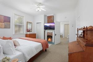 巴吞鲁日Redstick Cottage的一间白色卧室,配有一张床和一个壁炉