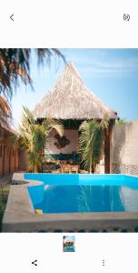 曼克拉IGUANA HOUSE的一个带游泳池和草屋的度假胜地